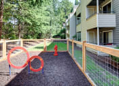 Thumbnail 27 of 34 - a fenced in pet park play area with a red fire hydrant and agility circles at 2000 Lake Washington Apartments, Renton, Washington