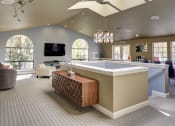 Thumbnail 32 of 34 - Resident clubhouse with comfortable seating, arched windows, a television, and a staircase in the center of the room leading to downstairs area at 2000 Lake Washington Apartments, Renton