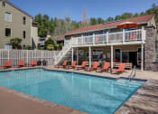 Thumbnail 28 of 34 - a swimming pool with orange chairs in front of resident clubhouse at 2000 Lake Washington Apartments, Renton, WA, 98056