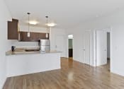 Thumbnail 18 of 46 - an empty living room with a kitchen and a door to a hallway at The Parker Apartments, Portland, 97209