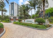 Thumbnail 55 of 56 - a pathway leading to a building with palm trees and a fountain