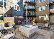 Thumbnail 3 of 27 - A patio with a hot tub surrounded by chairs and potted plants at 128 on State Apartments in WA 98033