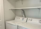 Thumbnail 20 of 34 - A white washing machine and dryer in a small laundry room at 2000 Lake Washington Apartments, Renton, 98056