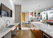 Thumbnail 24 of 42 - A modern kitchen with a large island and a flat screen TV mounted on the wall.