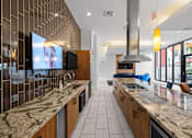 Thumbnail 11 of 42 - A modern kitchen with a marble countertop and a television mounted on the wall.
