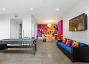 Thumbnail 23 of 42 - A pool table is in a room with a couch and a television.