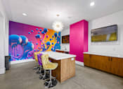 Thumbnail 13 of 42 - A brightly colored mural in a room with a bar and stools.