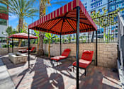 Thumbnail 31 of 42 - A red and white striped umbrella is over a table with two red chairs.