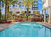 Thumbnail 33 of 42 - A swimming pool surrounded by palm trees and red lounge chairs.