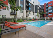 Thumbnail 35 of 42 - A pool surrounded by a patio with chairs and a table.