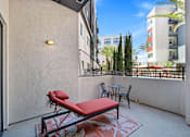 Thumbnail 7 of 42 - A balcony with a red couch and a table.