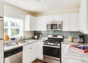 Thumbnail 14 of 28 - a kitchen with stainless steel appliances and white cabinets at Residences at Stevens Pond, Saugus, 01906