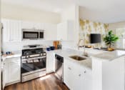 Thumbnail 27 of 28 - a white kitchen with stainless steel appliances and marble counter tops at Residences at Stevens Pond, Saugus, Massachusetts 01906