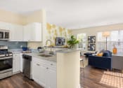 Thumbnail 20 of 28 - a kitchen with an island and a living room with a couch at Residences at Stevens Pond, Saugus, 01906