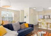 Thumbnail 25 of 28 - a living room with a blue couch and a kitchen at Residences at Stevens Pond, Saugus, MA