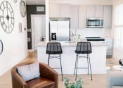 Thumbnail 1 of 39 - a white kitchen with bar stools and a counter at The Merchant Apartments, Charleston, SC