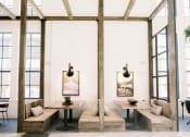 Thumbnail 25 of 39 - Indoor wooden pergola with wooden beams and two tables with benches on either side and oversized windows at The Merchant Apartments, Charleston, SC, 29403