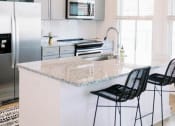 Thumbnail 3 of 39 - a kitchen with a marble counter top and a refrigerator at The Merchant Apartments, Charleston, SC