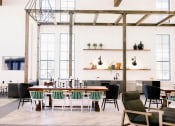 Thumbnail 23 of 39 - Resident lounge with high ceilings and wooden pergola with various cafe seating and farm tables at The Merchant Apartments, South Carolina