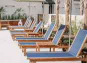 Thumbnail 18 of 39 - a row of lounge chairs with umbrellas in front of the soothing pool at The Merchant Apartments, Charleston