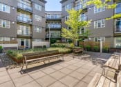 Thumbnail 4 of 28 - a courtyard with two benches and a tree in front of an apartment building at 128 on State, Washington, 98033
