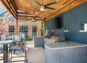 Thumbnail 37 of 40 - a covered patio with a grill and a table with chairs at Aston at Cinco Ranch, Texas