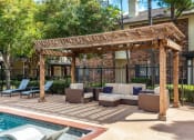 Thumbnail 35 of 40 - a covered patio with couches and chairs next to a pool at Aston at Cinco Ranch, Katy