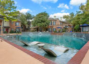 Thumbnail 34 of 40 - a swimming pool with two lounge chairs in front of a building at Aston at Cinco Ranch, Katy, 77450