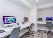 Thumbnail 18 of 19 - A white desk with a computer monitor and two chairs.
