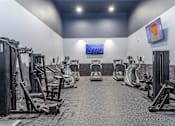 Thumbnail 17 of 19 - A gym with a variety of exercise equipment including treadmills, stationary bikes, and weight machines.