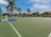 Thumbnail 13 of 19 - A tennis court surrounded by palm trees and residential buildings.