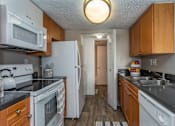Thumbnail 3 of 19 - A kitchen with white appliances and wooden cabinets.