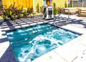 Thumbnail 13 of 17 - a hot tub in a pool next to a patio with furniture at Skyview Apartments, Colorado