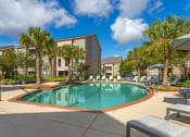 Thumbnail 24 of 30 - a swimming pool with palm trees and a building in the background at Summerwind, Texas, 77584