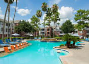 Thumbnail 18 of 29 - a large swimming pool with orange chairs in front of apartment buildings at Veranda at Centerfield, Texas
