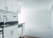 Thumbnail 6 of 21 - A kitchen with white cabinets and a grey countertop at Skye at Belltown Apartments, Seattle, Washington