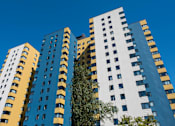 Thumbnail 1 of 21 - A tall building with a blue and yellow facade stands against a clear sky at Skye at Belltown Apartments, Washington