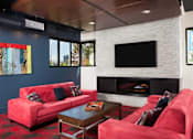 Thumbnail 12 of 21 - A living room with a fireplace and a television at Skye at Belltown Apartments, Seattle, WA