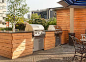 Thumbnail 10 of 21 - A wooden outdoor kitchen with a grill and sink at Skye at Belltown Apartments, Seattle, 98121