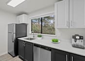 Thumbnail 24 of 25 - A kitchen with a black fridge and a white counter at Brackett Apartments, Edmonds