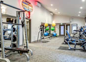 Thumbnail 5 of 25 - A gym with a variety of equipment including treadmills, weights, and exercise balls at Brackett Apartments, Edmonds, WA