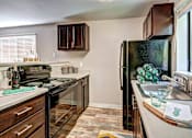 Thumbnail 16 of 25 - A kitchen with a black refrigerator and wooden cabinets at Brackett Apartments, Edmonds, WA, 98020