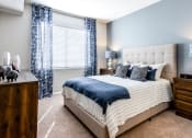 Thumbnail 17 of 33 - a bedroom with a bed and a window with blue curtains at The links at Plum Creek Apartments, Castlerock Colorado