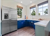 Thumbnail 64 of 105 - A modern kitchen with a stainless steel refrigerator and blue cabinets.