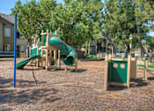 Thumbnail 85 of 105 - A playground with a green slide and a wooden structure.