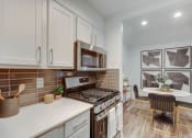 Thumbnail 6 of 35 - a kitchen with white cabinets and a table and a stove