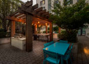 Thumbnail 43 of 46 - a wooden pergola with a turquoise table and chairs on a brick patio at The Parker Apartments, Portland, OR, 97209