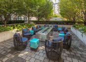 Thumbnail 44 of 46 - a seating area with wicker chairs and blue tables on a brick patio at The Parker Apartments, Portland, OR, 97209