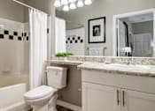 Thumbnail 10 of 38 - Bathroom with granite countertop and white cabinetry at Wyndchase Aspen Grove Apartments, Tennessee, 37067
