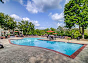 Thumbnail 19 of 38 - Pool area with patio furniture and orange umbrellas at Wyndchase Aspen Grove Apartments, Franklin, 37067
